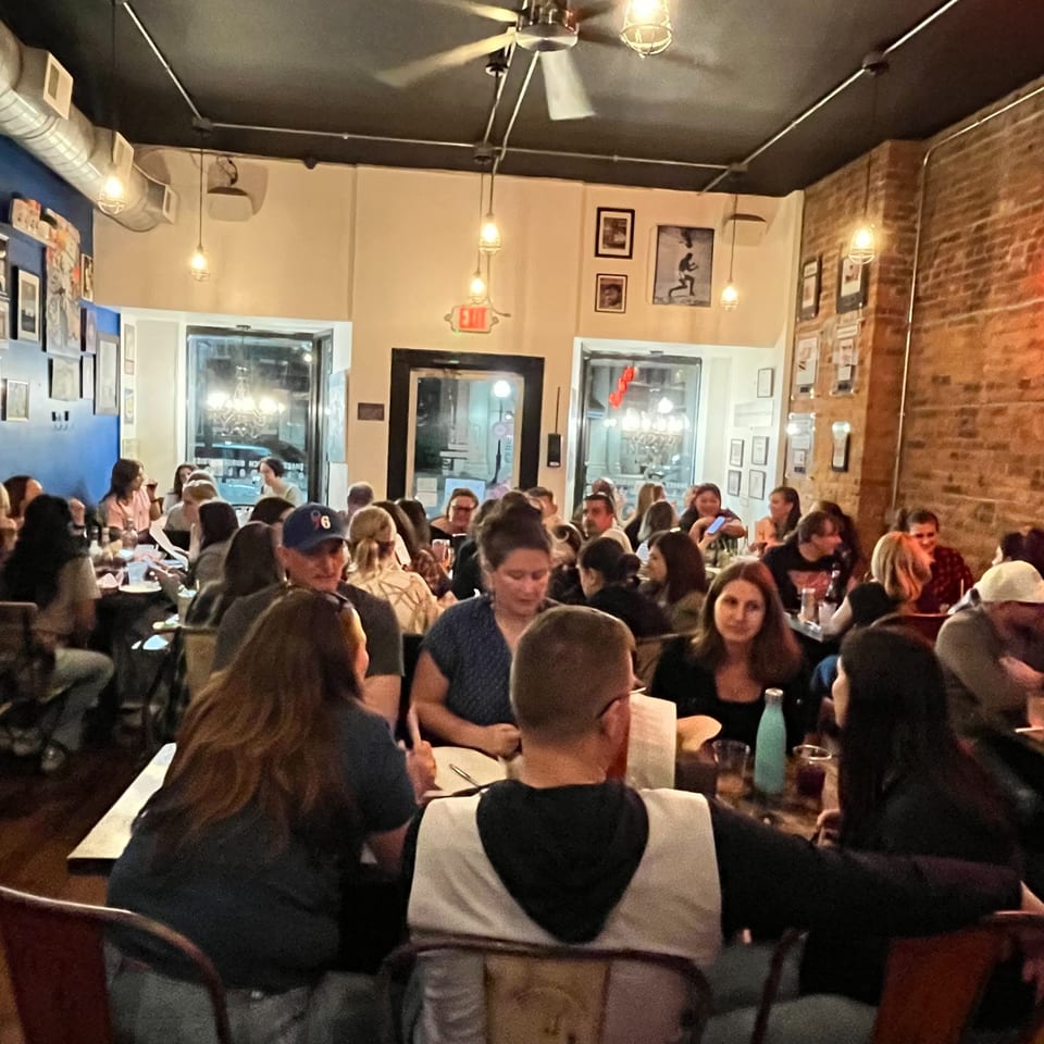 A bustling Urban Burger dining room filled with diverse patrons enjoying their meals under warm lighting.