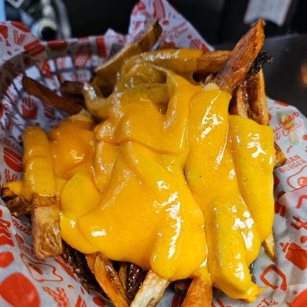 Cheesy fries from Urban Burger, served in a branded paper-lined basket.